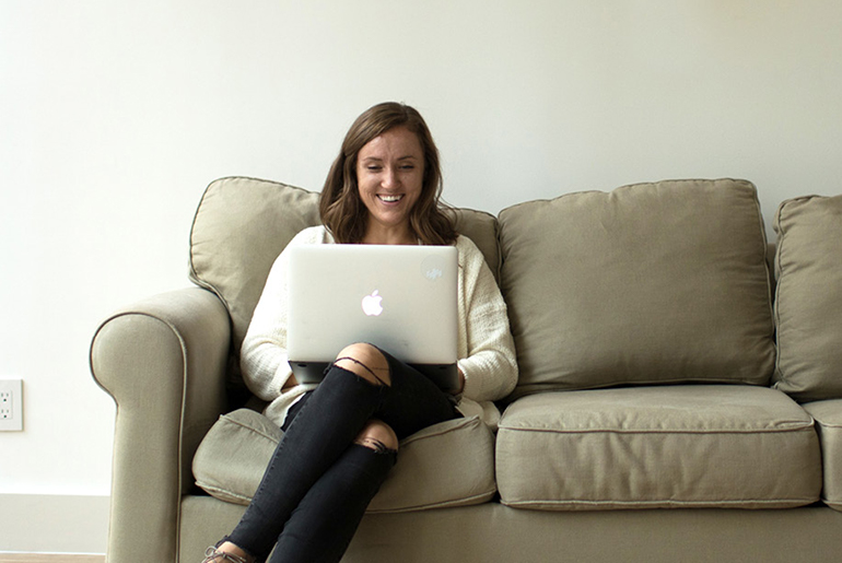 Meghan Easley, MAT Alumni, working on laptop on couch